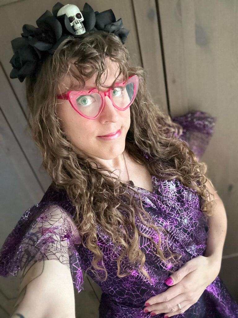 Me in a frilly purple dress with sparkly spiderweb designs on it, and a headband with a skull and black roses.