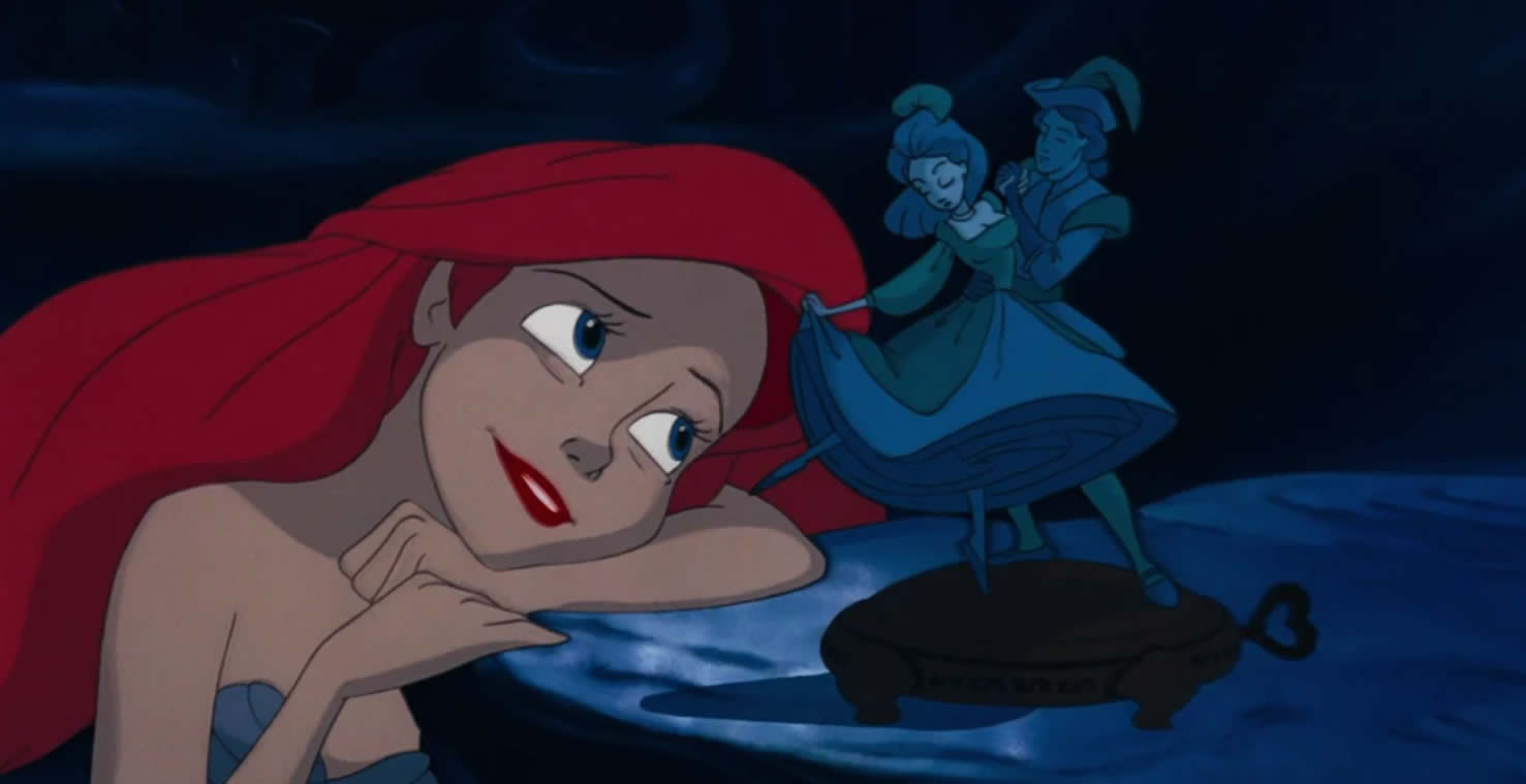 Ariel, from Disney's animated Little Mermaid movie, looking longingly at a statue of a man and woman dancing.
