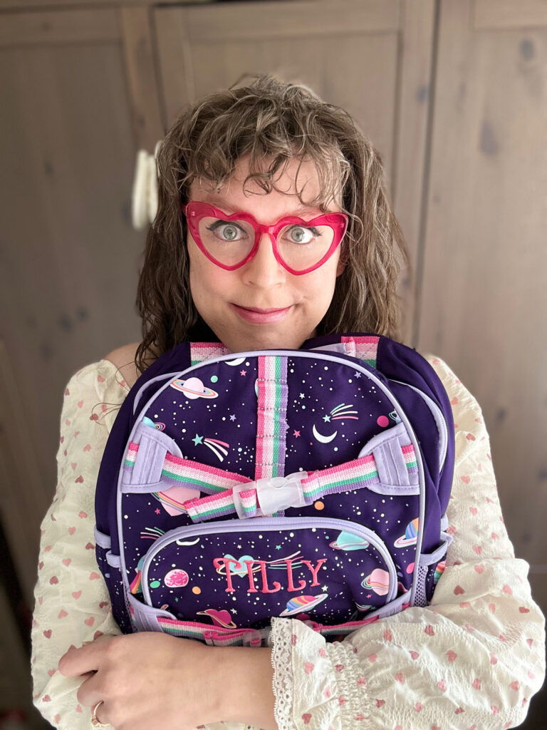 Me hugging my girly space backpack in front of me, smiling.