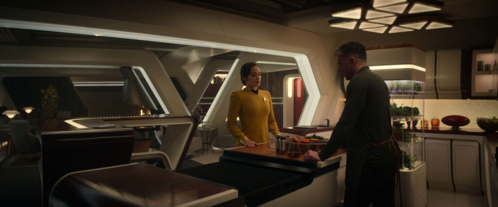 Captain Batel talking to Captain Pike in his quarters, while he cooks