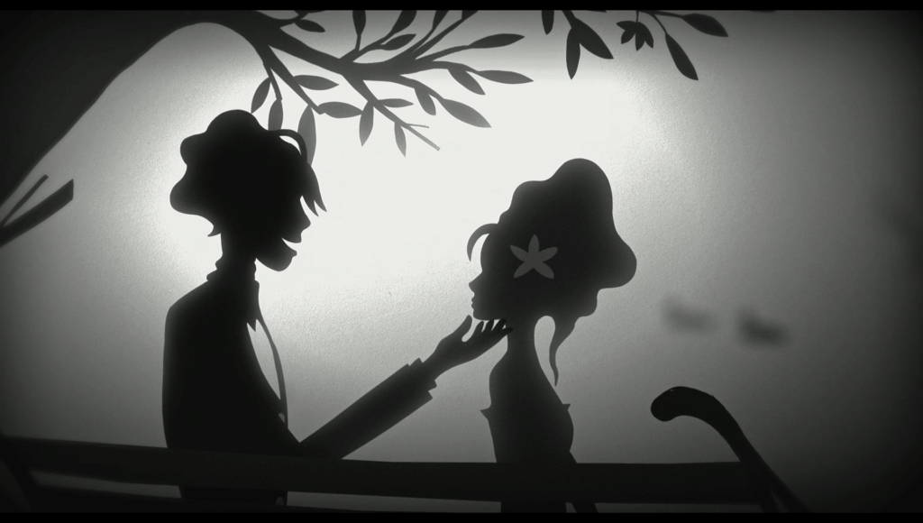 Still from a black and white animation of a man and a woman sitting on a bench in a park. The man is on the left, the woman on the right. The man has put aa flower in the woman’s hair.