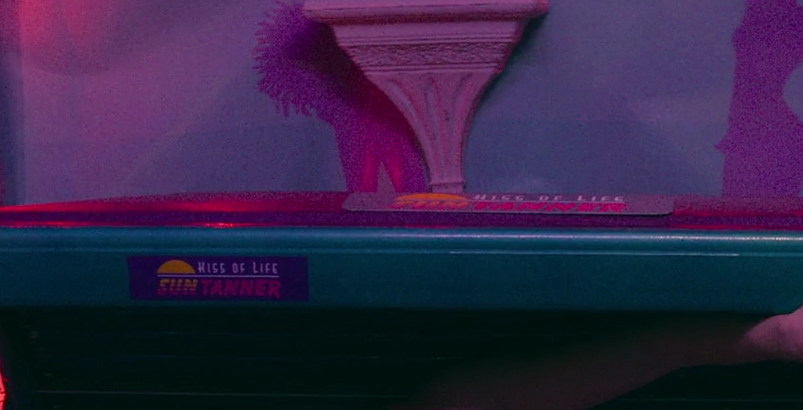 The tanning bed label says “Kiss of Life sun tanner”.