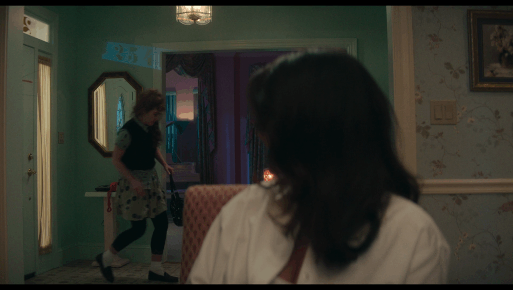 Lisa entering the house in the background as Taffy turns back to look at her from the foreground. Above Lisa in blue lights, from light shining through a window with the house’s address above the door, is the number 254.