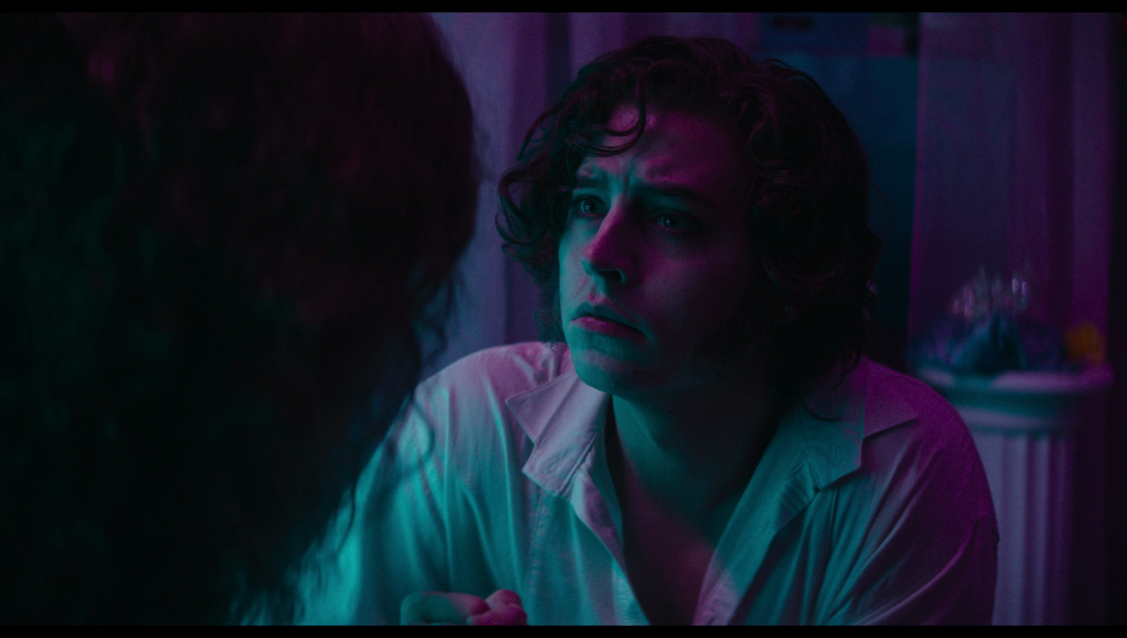 Frank, looking a little sad and awash in pink and blue light.