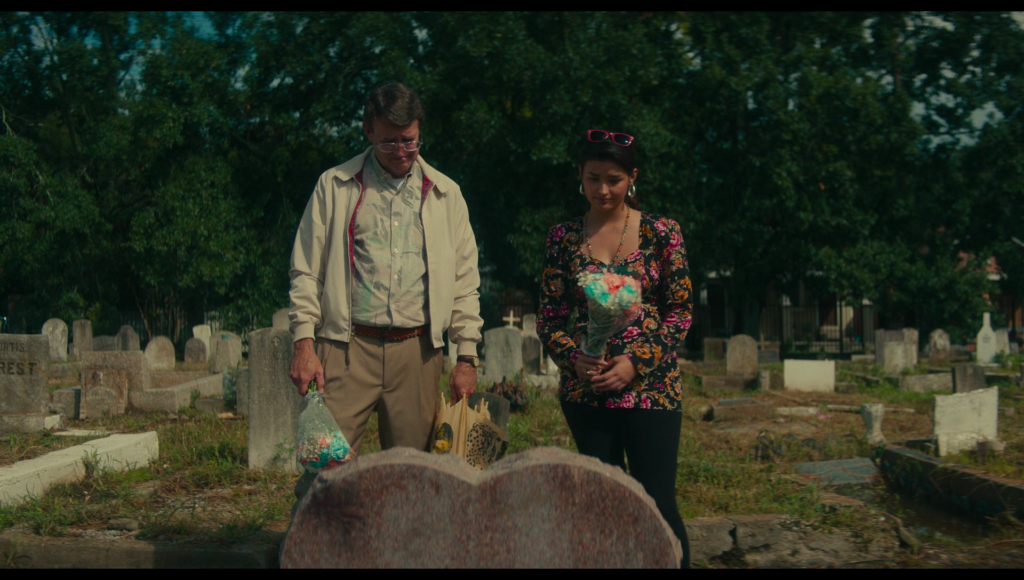 Taffy and Dad at Lisa’s grave, holding white, pink, and blue flowers.