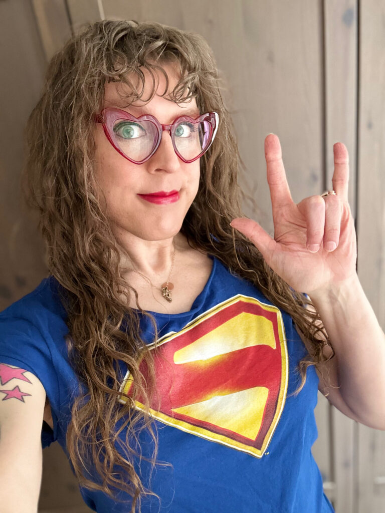 Me in my James Gunn's Superman tee, making the "i love you" hand sign