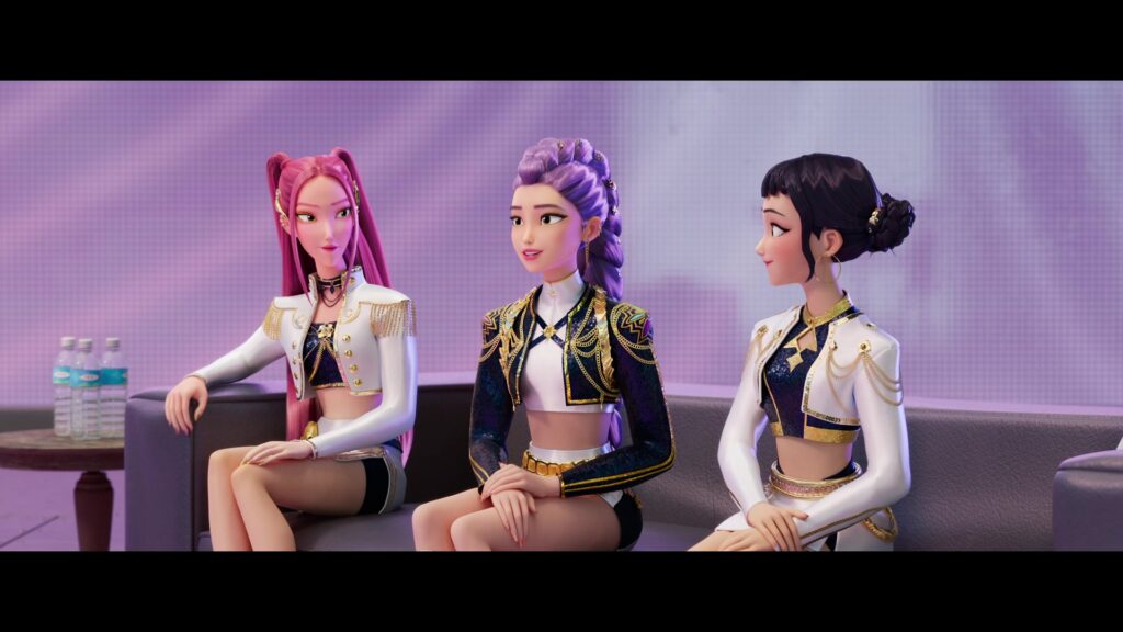 Mira, Rumi, and Zoe in their "Golden" outfits, sitting on a couch as they're interviewed